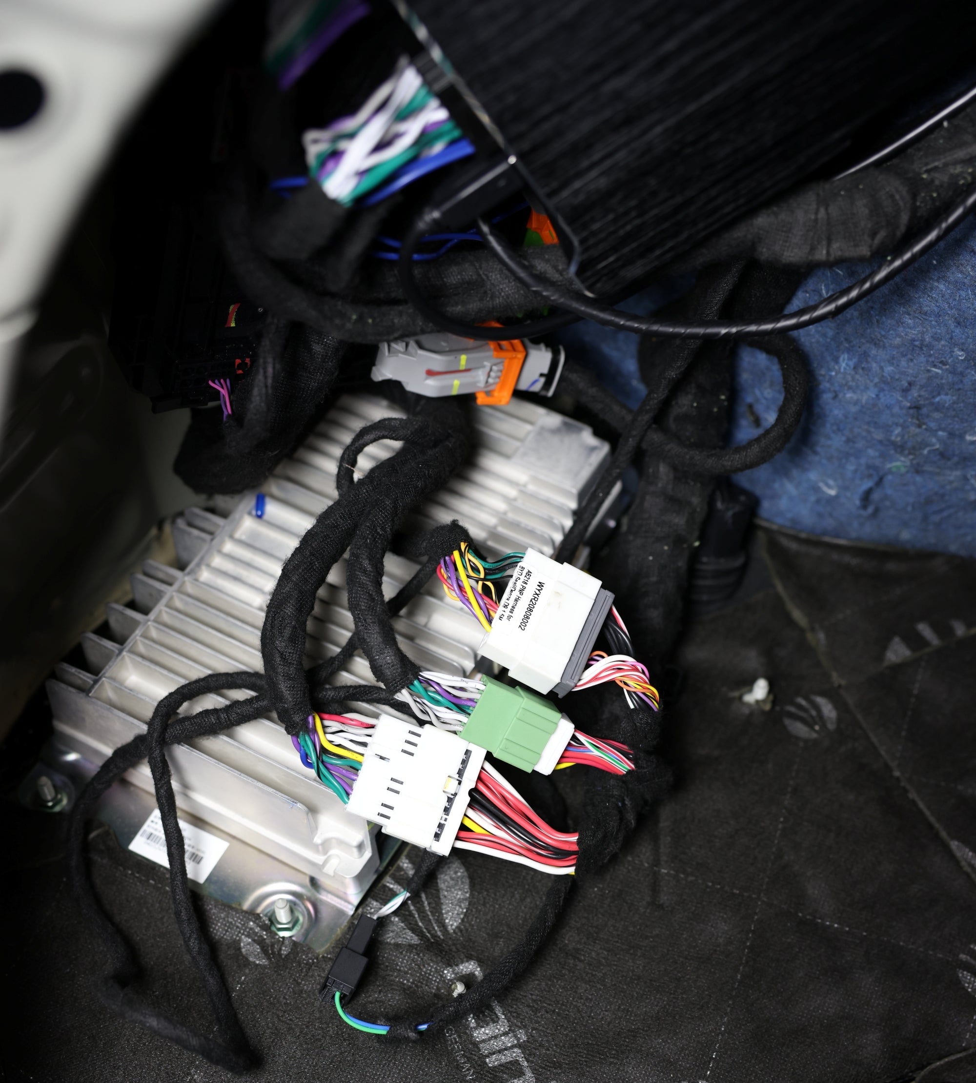 Car interior with wiring harness and components on a black mat